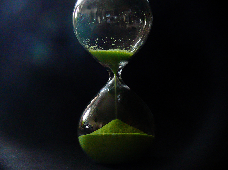 Hourglass with Green Sand on Black Background